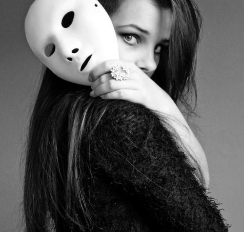 A woman looking towards the viewer while holding a white mask